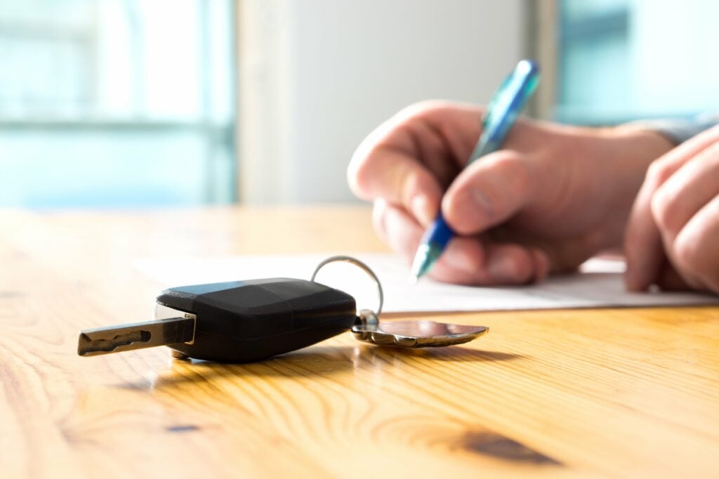 Man signing a vehicle lease contract