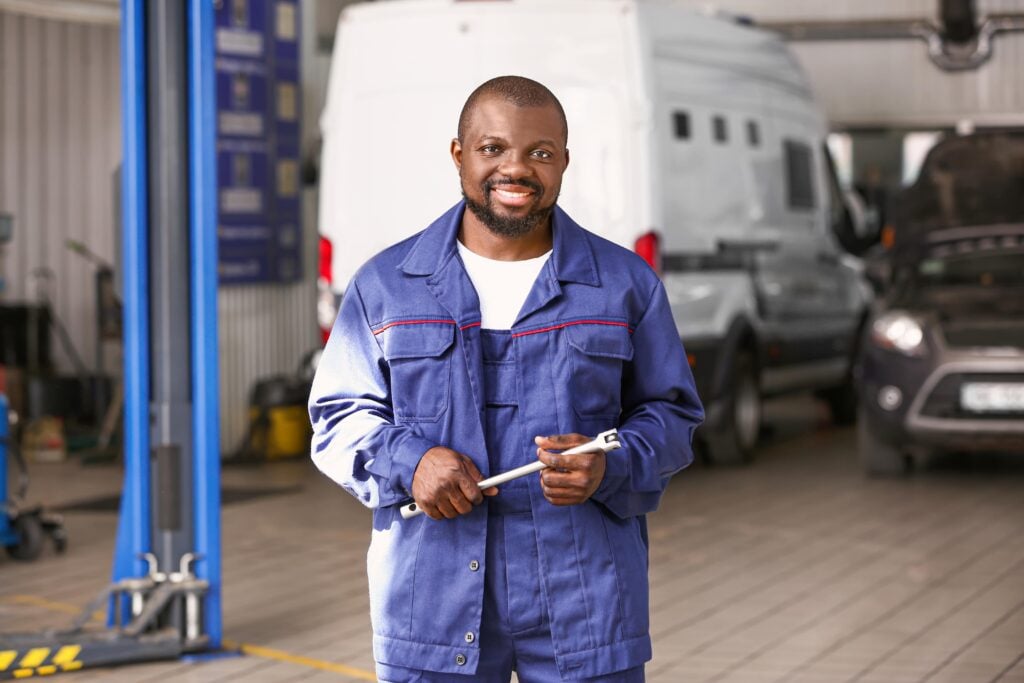 Mechanic standing in the vehicle rapair shop with a commercial van in the background