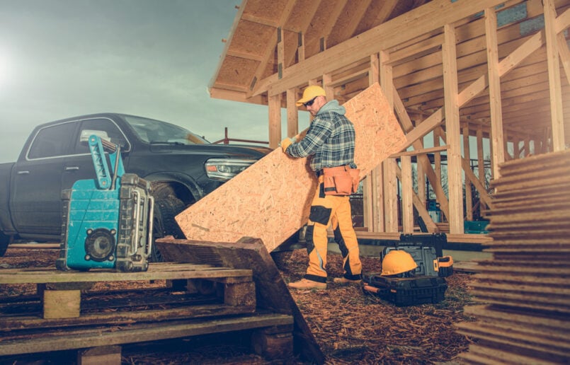 double-cab-pickup-truck-tax-changes-blog-image Workman holding a sheet of plywood next to a double cab pickup