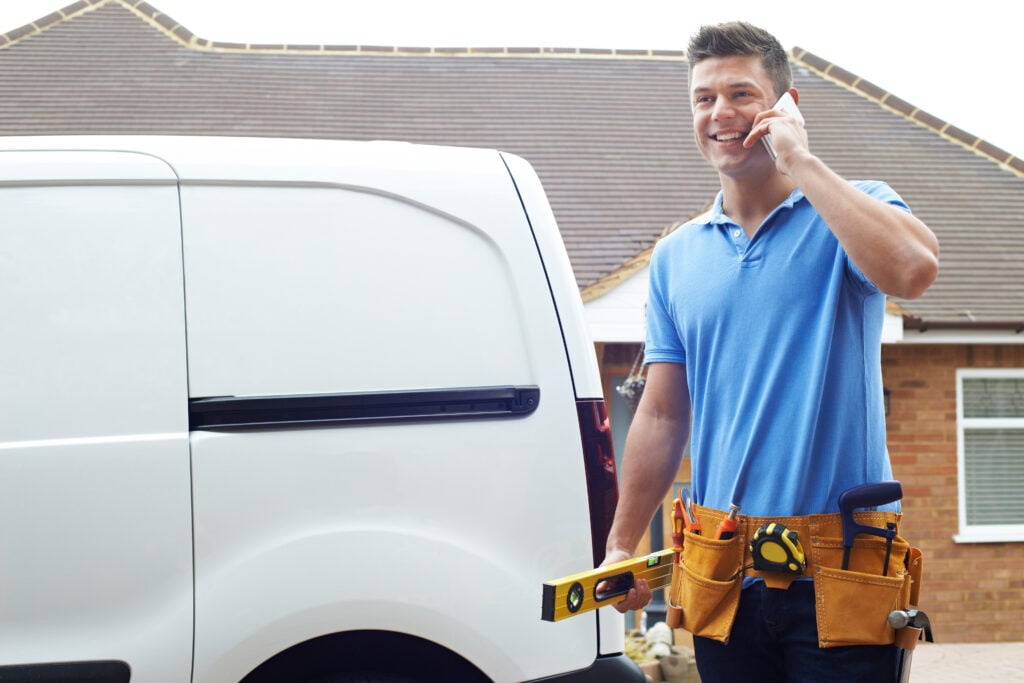 Builder,With,Van,Talking,On,Mobile,Phone,Outside,House
